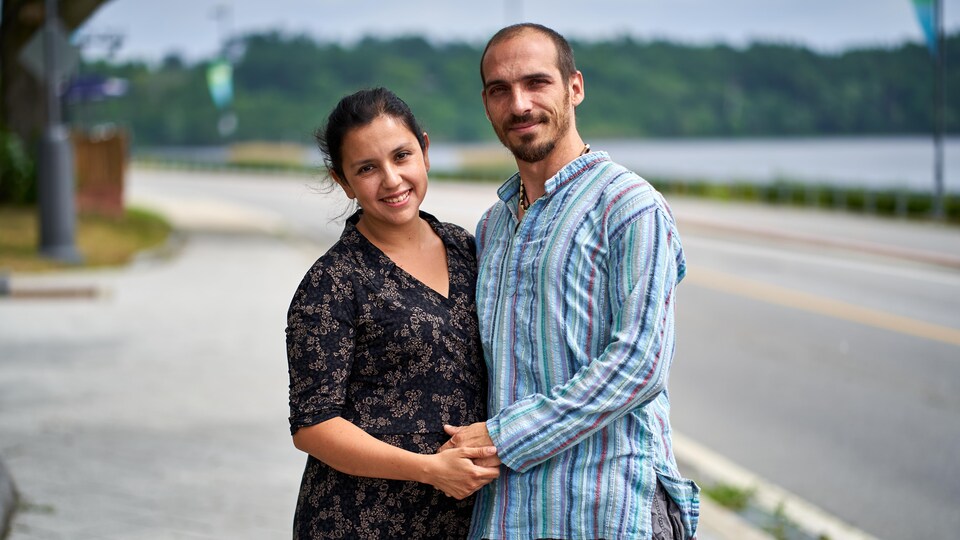 Jennifer et Alexandre posent fièrement main dans la main devant une rivière.