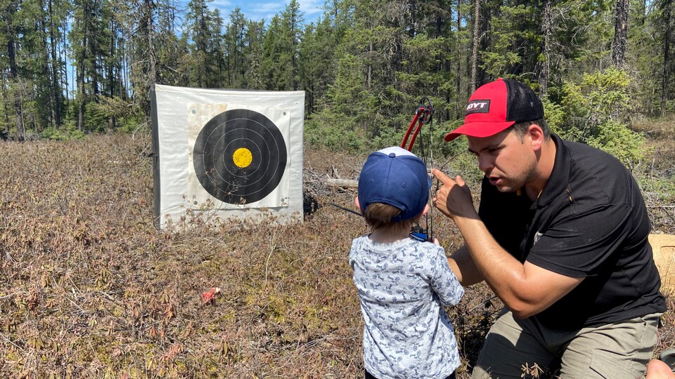 Alexandre Dupuis enseigne les rudiments du tir à l'arc à un jeune visiteur.
