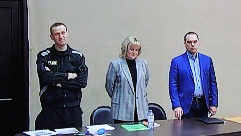 Alexei Navalny,  debout, les bras croisés, accompagné d'une femme et d'un homme.
