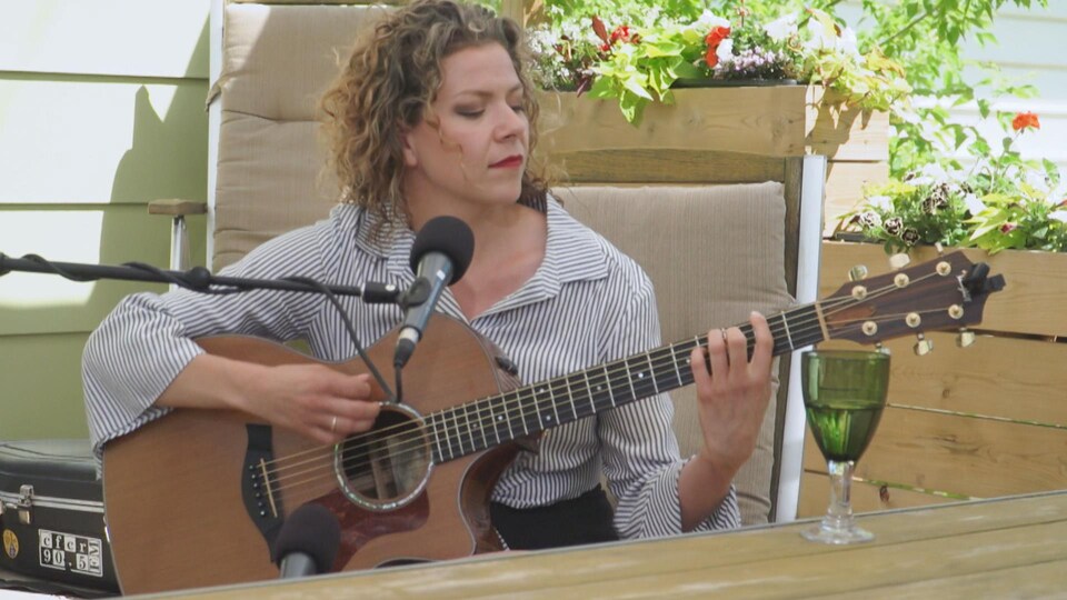 Alexis Normand à la guitare, sur une terrasse extérieure.