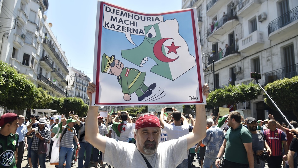 Un homme brandit une affiche dénonçant l'intrusion de l'armée dans le pouvoir politique.