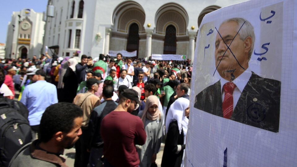 Un portrait défiguré du président du Conseil constitutionnel algérien Tayeb Belaiz est présenté alors que des étudiants prennent part à une manifestation à Alger, le 16 avril 2019.