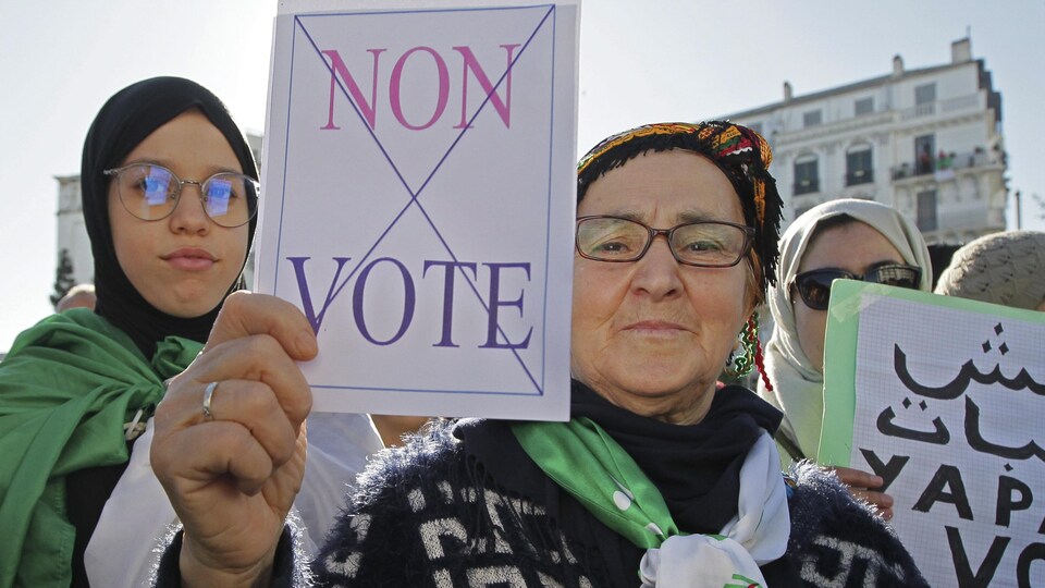 Une manifestante algérienne brandit une pancarte sur laquelle il est écrit « Non vote »