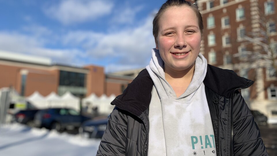 Une fille se laisse prendre en photo à l'extérieur d'un établissement.