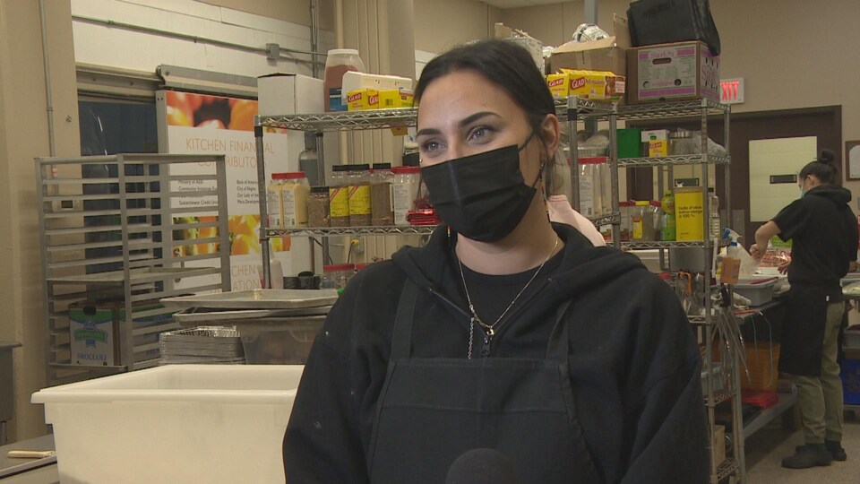Alicia Morrow porte un masque et est interviewée dans les locaux de l'organisme.