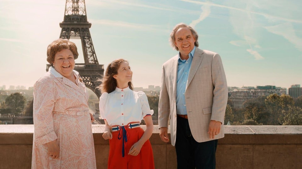 Les trois personnes posent devant la tour Eiffel à Paris.
