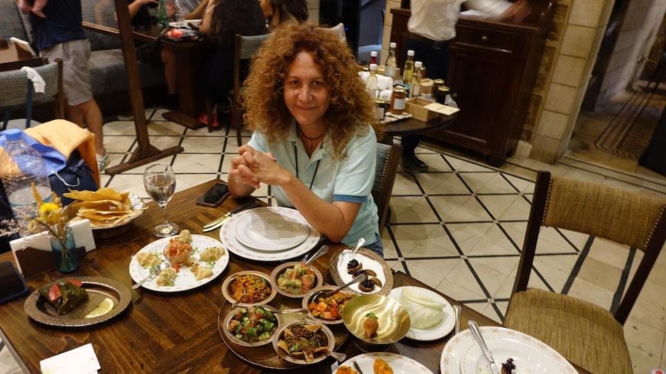 Une femme est assise à une table de restaurant devant de nombreux plats arméniens.