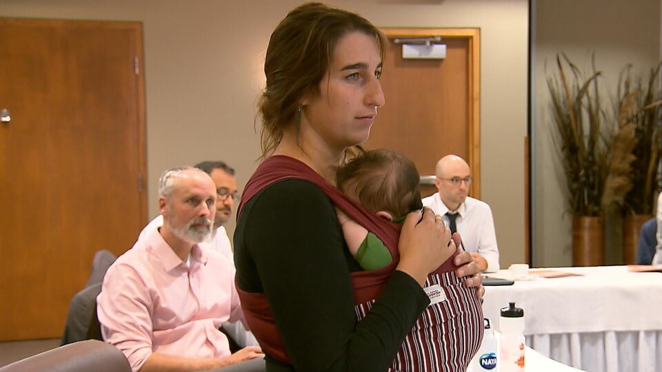 Elle assiste à une réunion avec son bébé dans les bras.