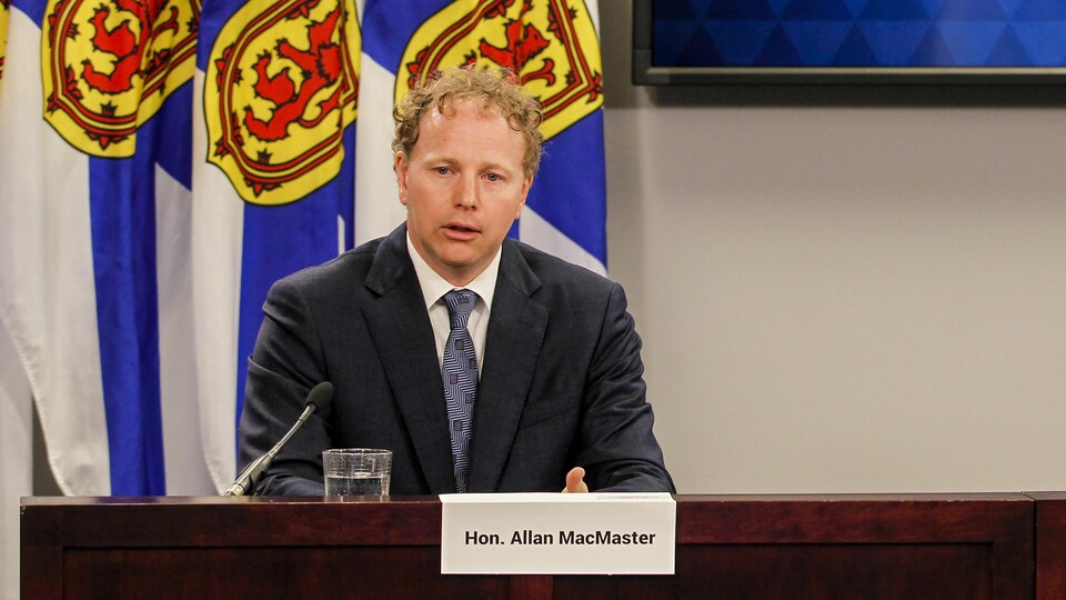 Allan MacMaster assis en conférence de presse.