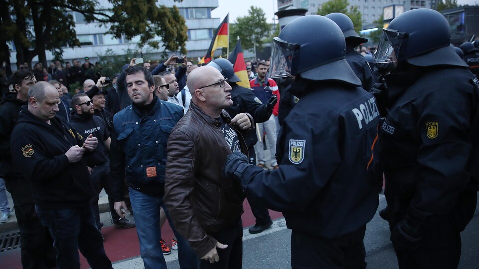 Un manifestant apostrophe un policier casqué en Allemagne.
