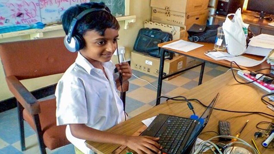 Un jeune participant devant un ordinateur ayant des écouteurs sur ses oreilles