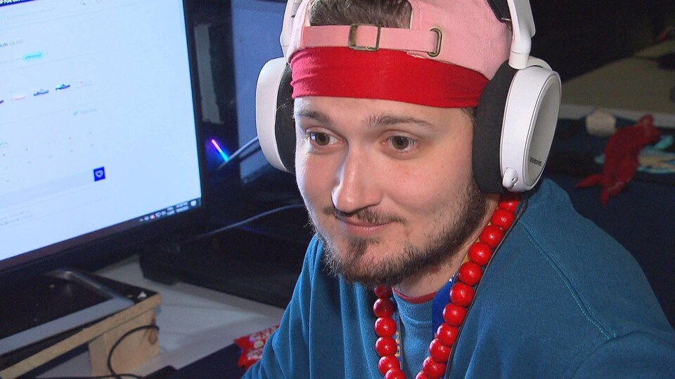 Alsenic porte une casquette rose à l'envers et un collier de grosses perles rouges dans le cou.