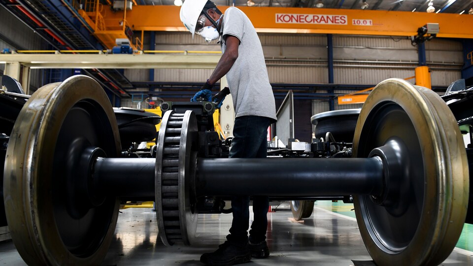 Un homme travaille sur du matériel roulant dans une usine.