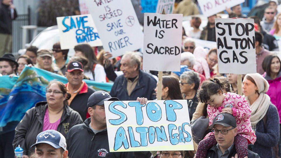 Groupe de personnes qui marchent en brandissant des pancartes dont le message dénonce le projet Alton Gas.