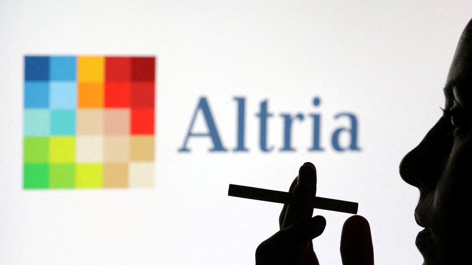 Une femme tient une cigarette devant le logo d'Altria.