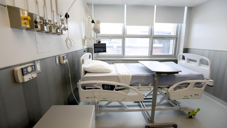 Une chambre d'hôpital vide où l'on voit du revêtement d'aluminium sur les murs.