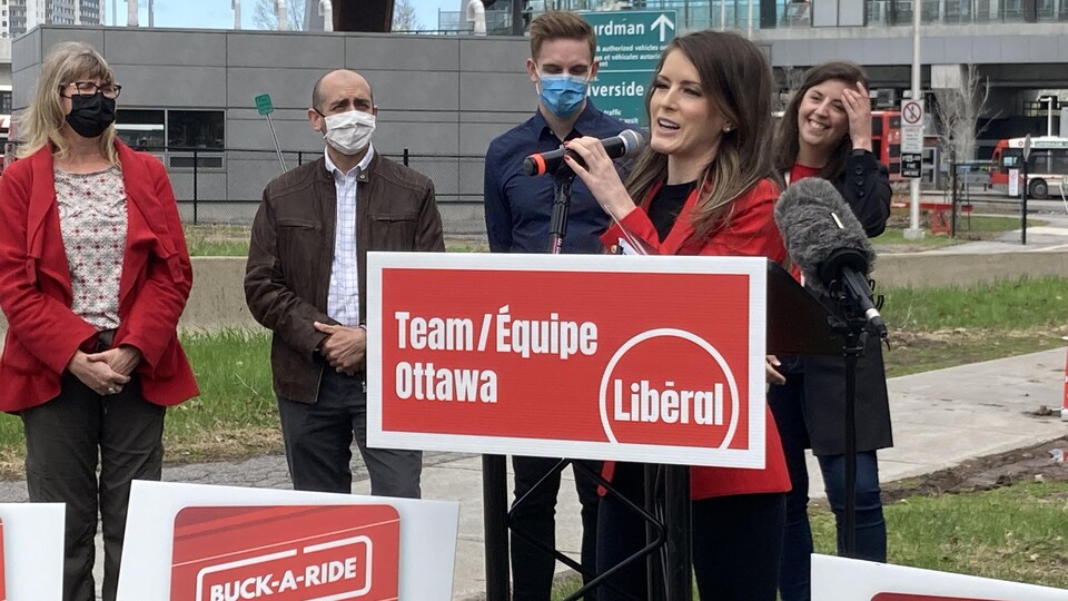 Derrière un panneau du Parti libéral de l'Ontario, Amanda Simard parle au micro avec des personnes en arrière-plan.
