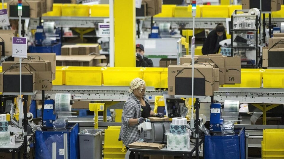 Une employée à une chaîne d'emballage d'Amazon, sans masque.
