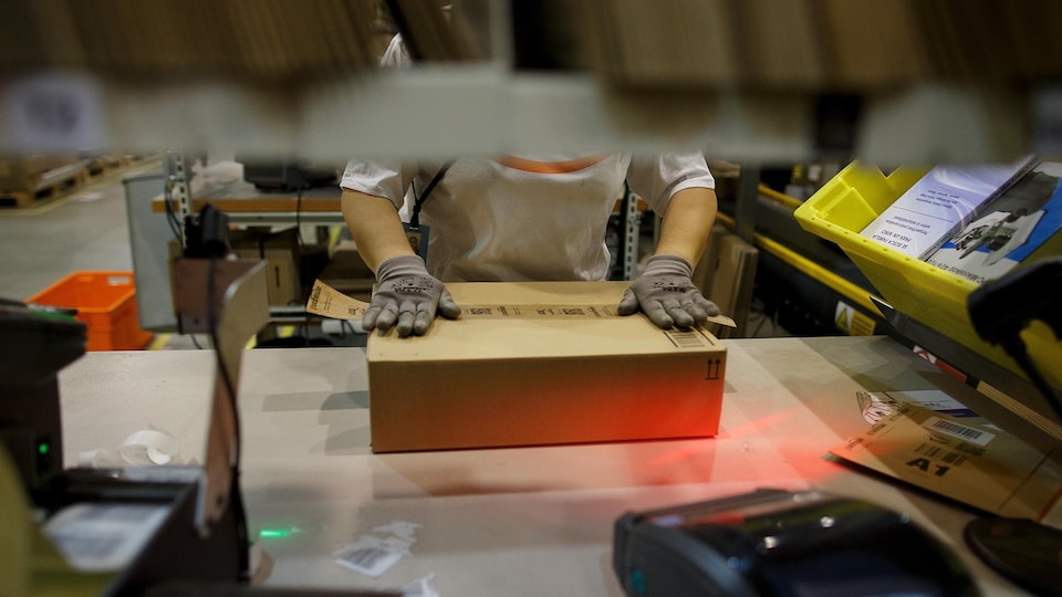 Un employé d'Amazon prépare un colis pour expédition dans un entrepôt de l'entreprise.