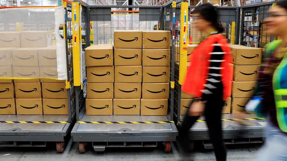 Une employée se promène à côté de boîtes dans un entrepôt d'Amazon.