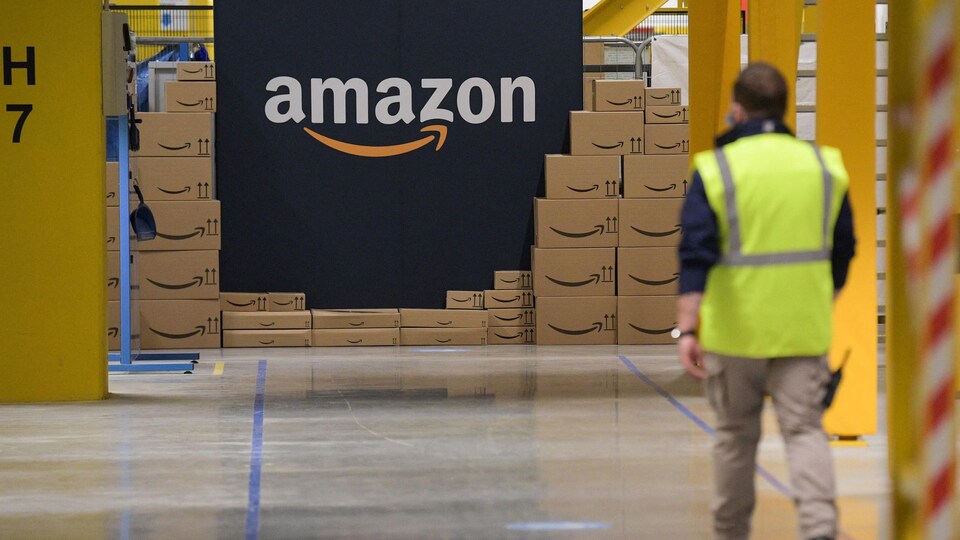 Un employé marche vers un mur affichant le logo d'Amazon.