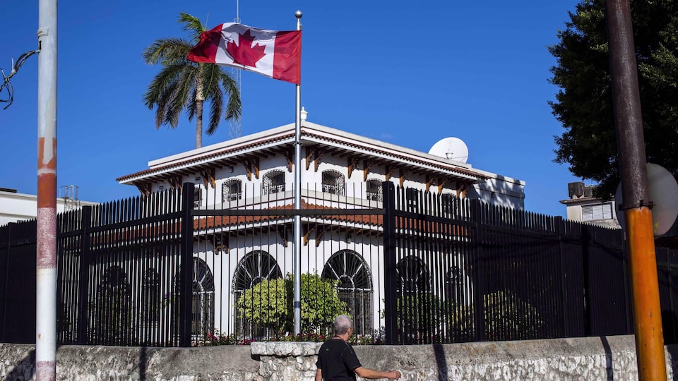 Un drapeau canadien flotte devant l'édifice clôturé de l'ambassade canadienne à Cuba.
