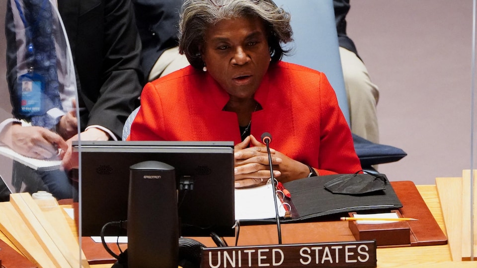 Linda Thomas-Greenfield sits at a table with a plate and microphone bearing the name of the United States.