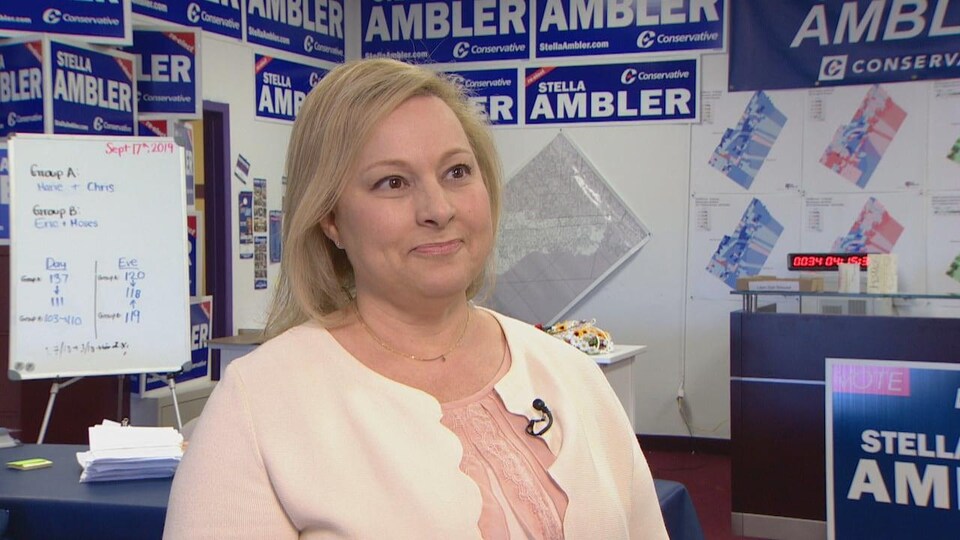 Stella Ambler devant des affiches électorales bleues portant son nom.