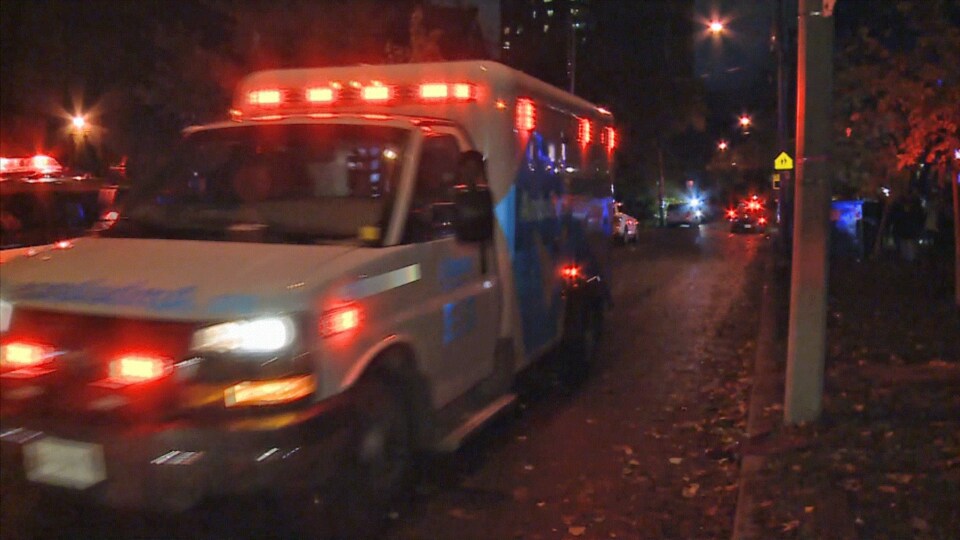 Une ambulance aux gyrophares allumés dans une rue.