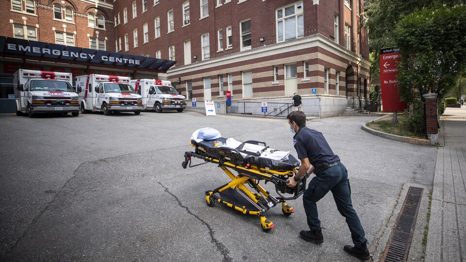 Un ambulancier pousse une civière devant un hôpital à Vancouver.