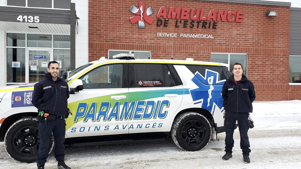 Deux ambulanciers devant leur véhicule.