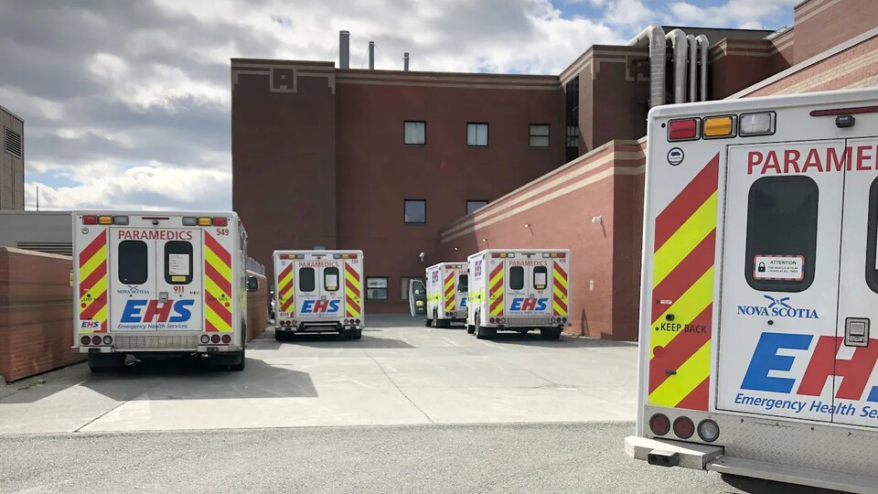 Plusieurs ambulances sont garées devant un hôpital.