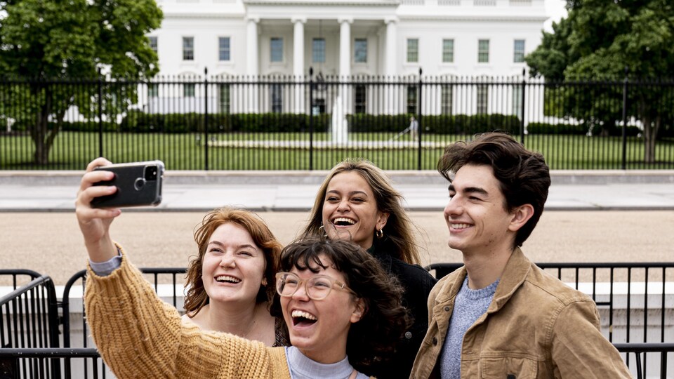 Tout sourire, quatre jeunes dans le parc Lafayette, où subsistent des barrières, se photographient devant la Maison-Blanche.