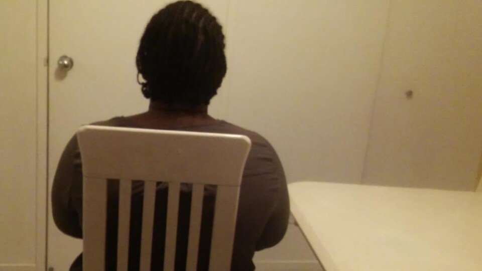 La femme assise sur une chaise, de dos.