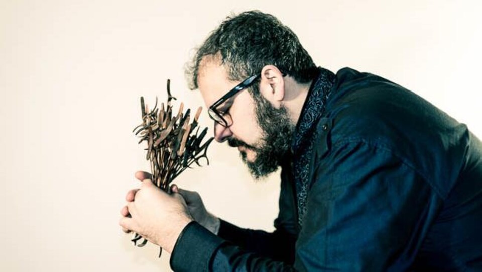 un homme avec un bouquet de plantes dans les mains, pensif, les yeux fermés