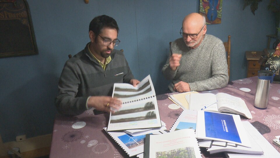 Amit Virmani, de Naveco Power, et Daniel Brassard, montrent une étude sur les éoliennes dans la région.