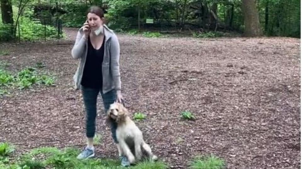 Amy Cooper parle au téléphone en tenant son chien par le collier.