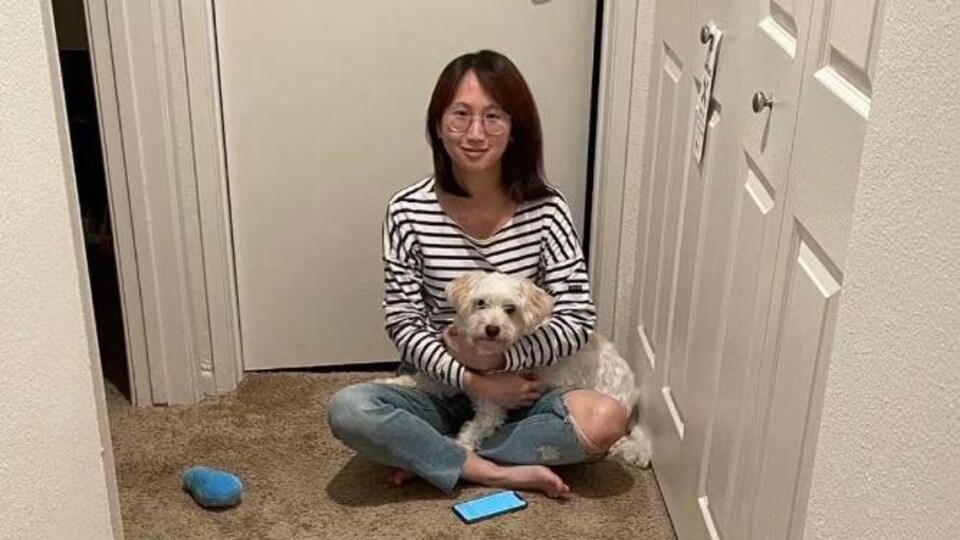 Une femme assise par terre avec un chien sur les genoux.