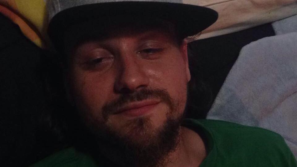 L'homme porte la barbe et la casquette, ainsi qu'un t-shirt aux couleurs des Celtics de Boston, une équipe de basketball.