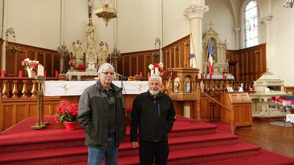 Deux hommes debout devant l'autel de l'église.