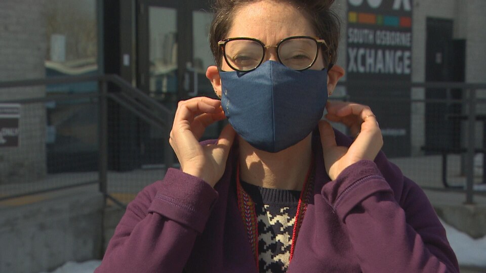 Une femme à lunettes porte un masque bleu.