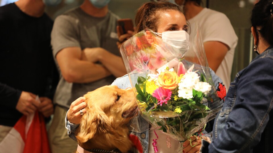 Andréanne holds a bouquet while flattering a dog.