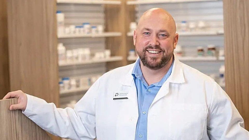 Un pharmacien en sarrau blanc dans sa pharmacie.