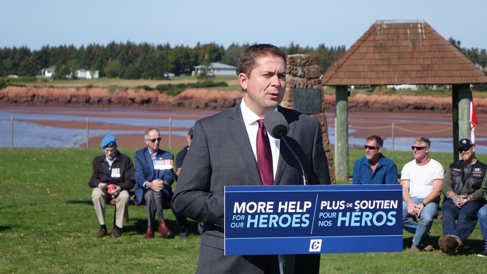 Andrew Scheer fait une annonce tandis que des vétérans canadiens sont assis loin derrière lui.