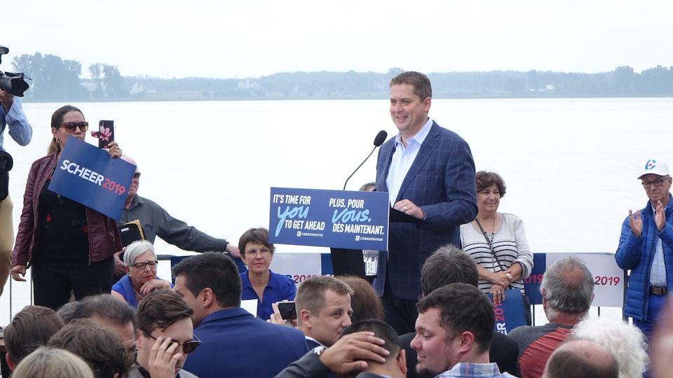 Andrew Scheer s'adresse au micro devant une foule réunie près d'une étendue d'eau.