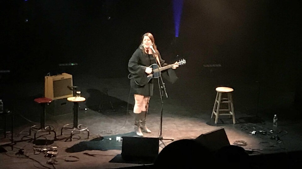 Andrina Turenne au micro avec sa guitare à la main.