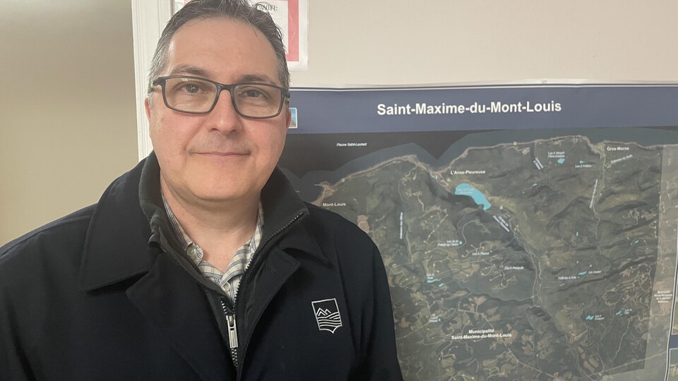 Claude Bélanger devant une carte de Saint-Maxime-du-Mont-Louis, en Haute-Gaspésie. 