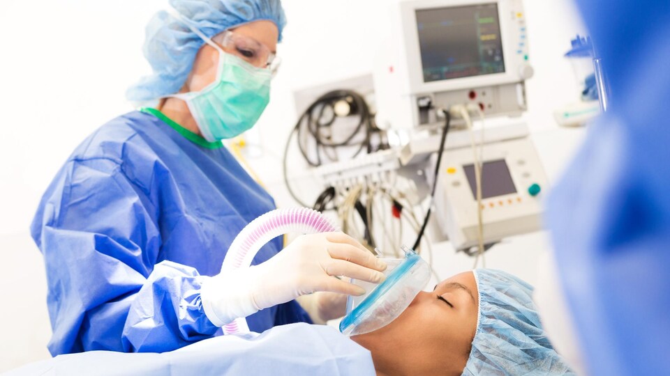 Une anesthésiste adulte utilise un équipement médical pour endormir une patiente.