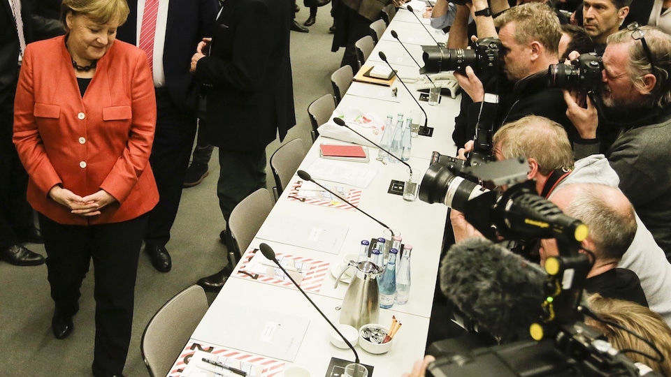 Angela Merkel est mitraillée par des photographes à son arrivée à la rencontre.