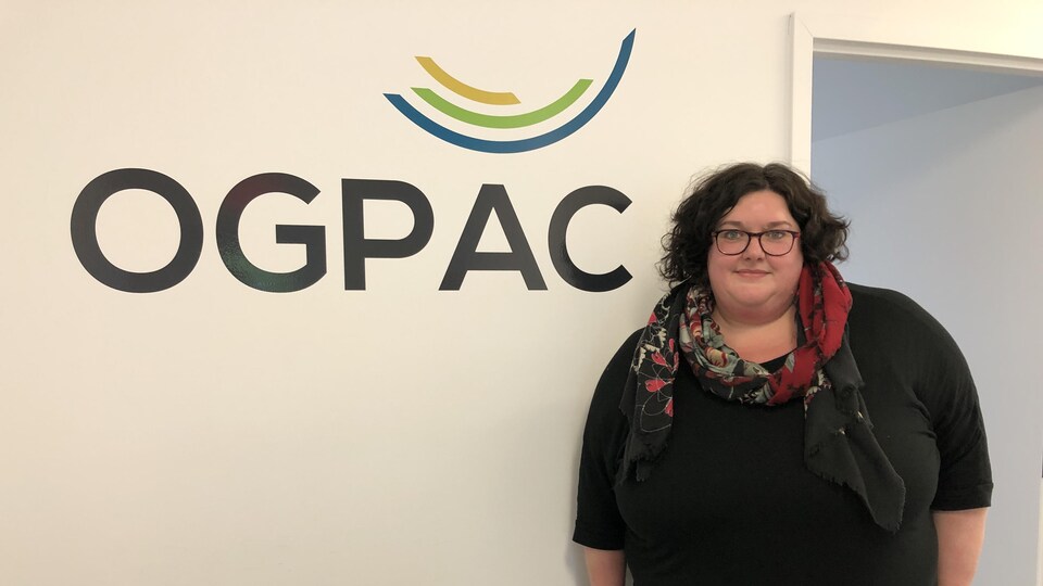 Anie Cayouette devant un mur où on voit le logo de l'OGPAC